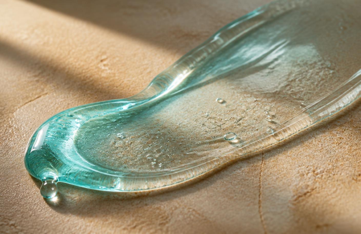 Close-up of a glossy amber serum texture drawn across a pale surface, representing a copper peptide formulation